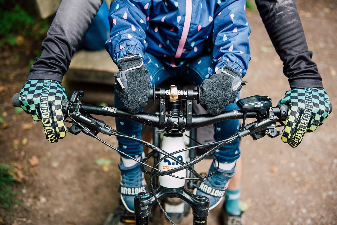 Aus der Lenkerperspektive Kind sitzt vorne im Kindersitz von Shotgun, erwachsende Person steuert, man sieht die behandschuhten Hände am Lenker